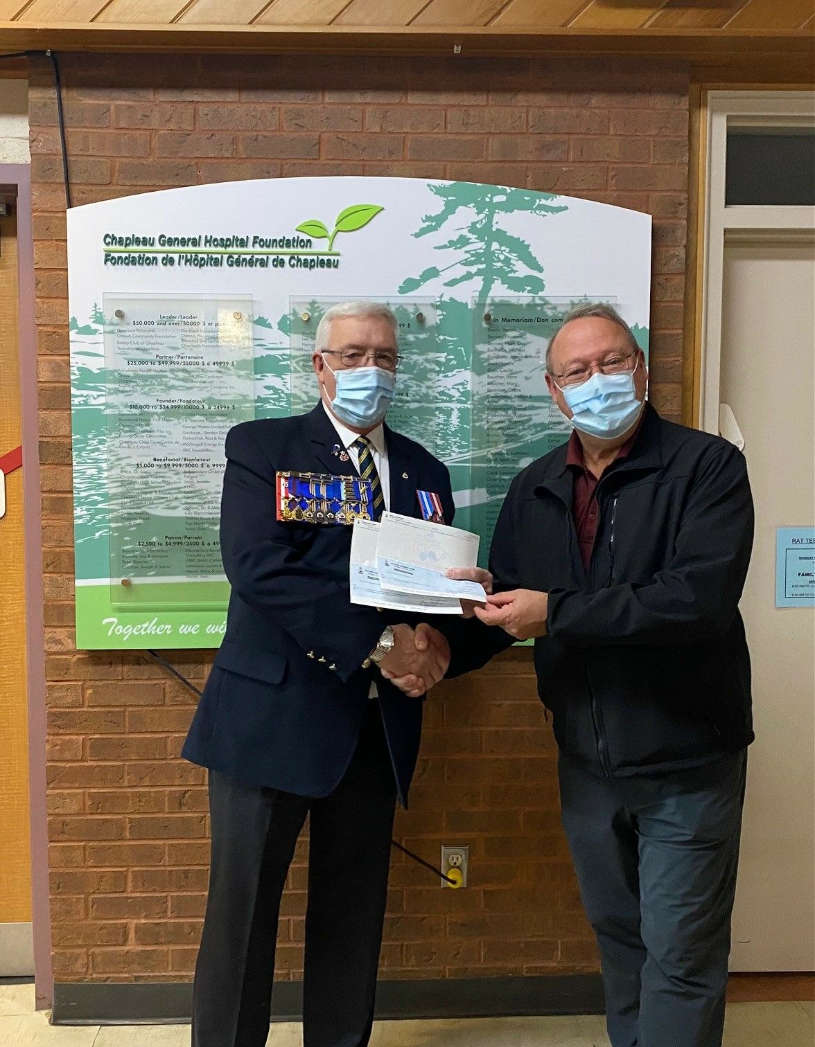 Andre Paquette and Luc Tessier holding giant donation cheque